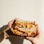 person holding brown bread with chocolate syrup