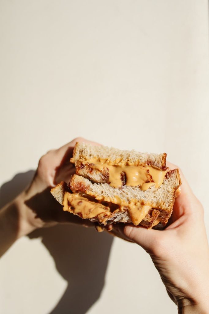 person holding brown bread with chocolate syrup